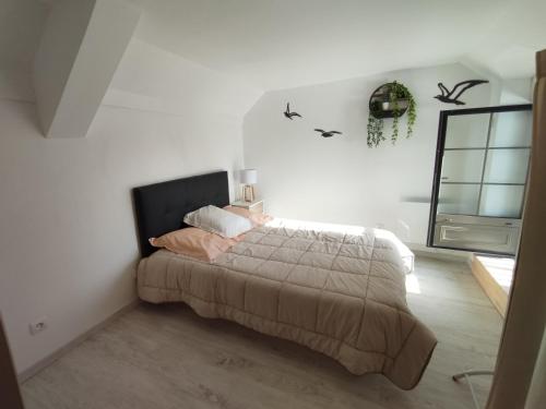 una camera da letto con un grande letto in una stanza bianca di Petit gîte bleu 