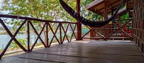 a hammock on a wooden bridge next to a river at Bon Tai Oasis Bungalows in Muang Không