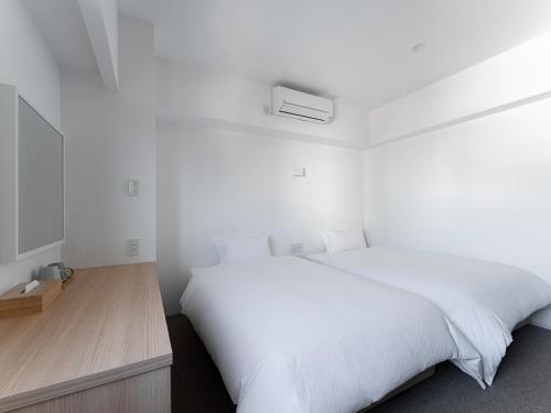 a bedroom with a white bed and a wooden desk at Kaname Inn Tatemachi in Kanazawa