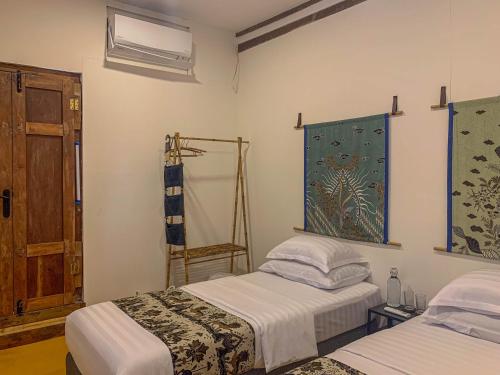 a bedroom with two beds and a window and a door at Yukke Tembi Homestay in Yogyakarta