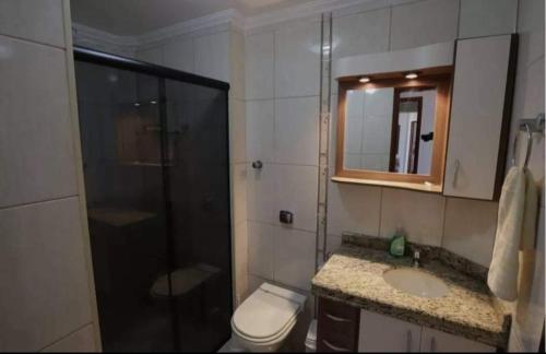 y baño con ducha, aseo y lavamanos. en Apartamento Praia de Mongaguá en Mongaguá