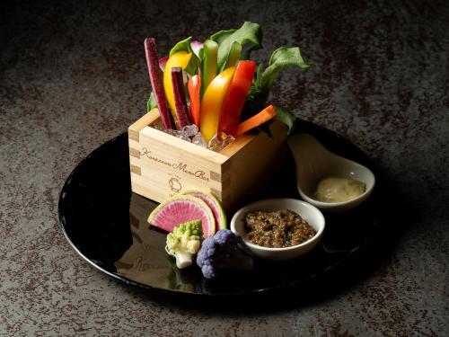 a box of vegetables on a plate with some dips at Kaname Inn Tatemachi in Kanazawa