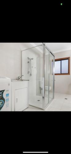 a white bathroom with a shower and a sink at 68 Frederick in Sydney