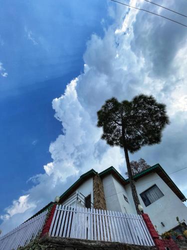 a tree on top of a white building with a sky at Panorama by Meraki - Entire villa with Himalayan View in Rānīkhet