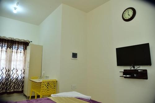 a bedroom with a tv on the wall and a bed at Coorg Lotus Villa in Madikeri