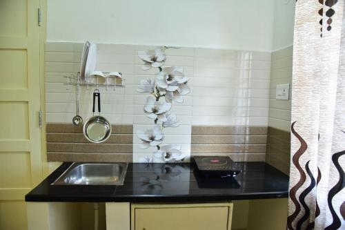 uma cozinha com um lavatório e um balcão com flores na parede em Coorg Lotus Villa em Madikeri