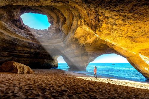 a person standing on a beach in front of a cave at Portimao Central Holiday Guesthouse in Portimão
