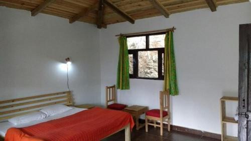 a bedroom with a red bed and a window at Ek Chidiya Cottage, Mukteswar in Mukteswar
