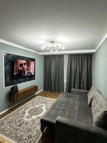 a living room with a couch and a flat screen tv at Однокомнатная квартира в центре города in Oral