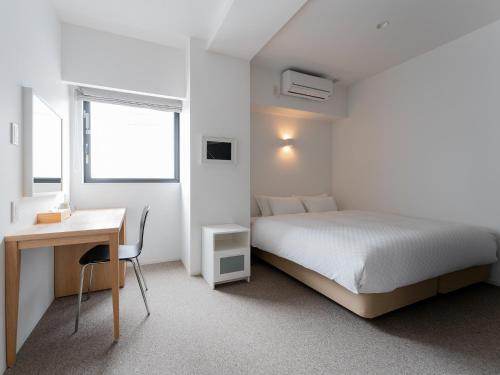 a white bedroom with a bed and a desk at Kaname Inn Tatemachi in Kanazawa