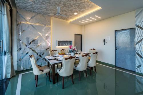 a dining room with a table and white chairs at SaffronStays Blueberry in Panchgani