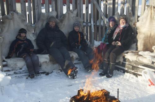 a group of people sitting around a fire in the snow at Seljenes Cottage in Russenes