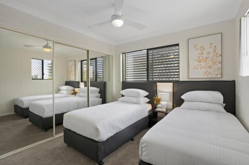 two beds in a room with mirrors at Comfy 2-Bedroom Family Apartment with Free Parking in Brisbane