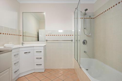 een witte badkamer met een douche en een wastafel bij Comfy 2-Bedroom Family Apartment with Free Parking in Brisbane