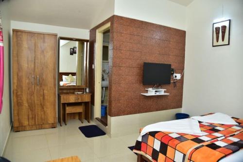 a bedroom with a bed and a tv on a wall at Coorg Lotus Villa in Madikeri
