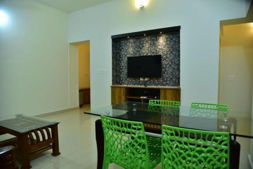 a dining room with a table and chairs and a television at Coorg Lotus Villa in Madikeri