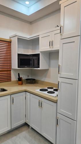 a kitchen with white cabinets and a stove top oven at Beachscape At Black River Ethlyn by the sea in Black River