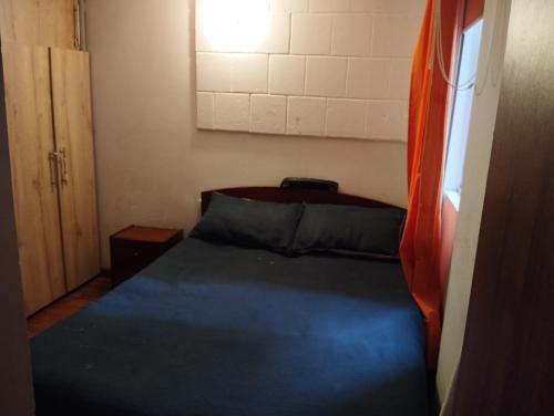 niewielka sypialnia z niebieskim łóżkiem i oknem w obiekcie Mirador de Fontibon w mieście Bogota