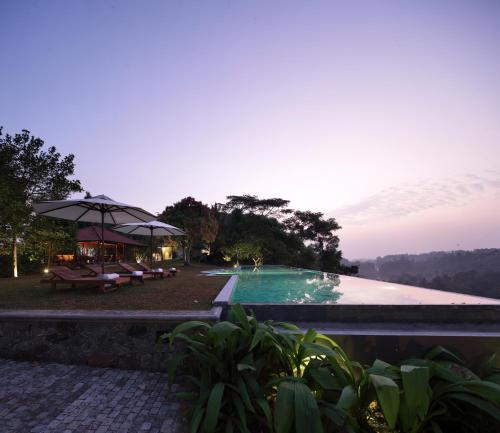 een zwembad met stoelen en parasols naast een resort bij Heavensa Luxury Villas in Galle