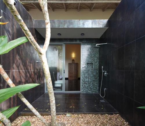 a bathroom with black tile and a tree in the foreground at Heavensa Luxury Villas in Galle