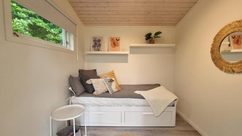 a small bedroom with a bed and a mirror at A Cozy Retreat Close to Lake in Hjärnarp