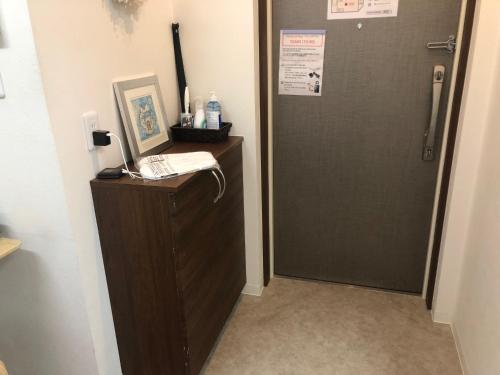 a bathroom with a shower and a door with a phone at Apartment Heights HANA in Sakai