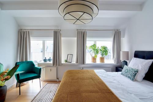 a bedroom with a bed and a chair and windows at Penthouse-Nordic-Citycenter-Balcony in Copenhagen