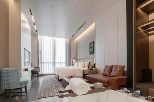 une chambre d'hôtel avec un lit et un canapé dans l'établissement Zhengzhou The Grand House, à Zhengzhou