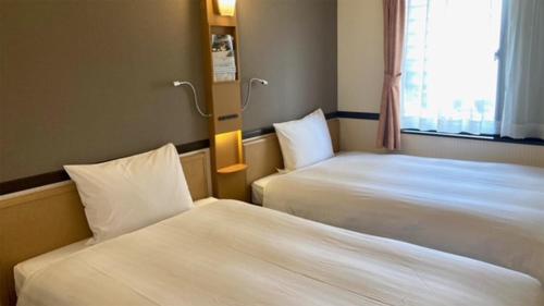 a hotel room with two beds and a window at Toyoko Inn Sendai Higashi-guchi No 2 in Sendai