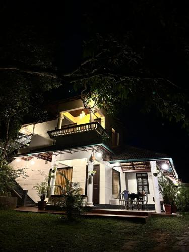 a white house with a balcony at night at Thoppil Homestay Munnar in Munnar