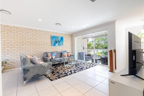 a living room with a couch and a tv at 1 75 Rocky Point Road fantastic holiday home with in Fingal Bay