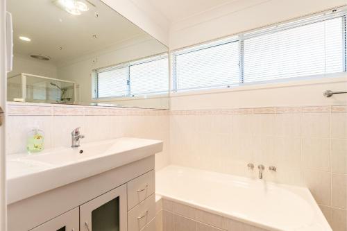 a white bathroom with two sinks and a mirror at 1 75 Rocky Point Road fantastic holiday home with in Fingal Bay