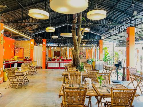 un restaurante con mesas y sillas de madera y un árbol en Central Privilege Hotel, en Siem Reap