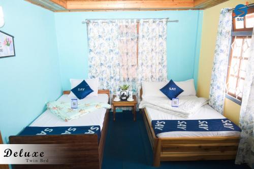 two beds in a room with blue walls at SAY Homes Grace in Namchi