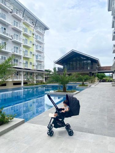 a baby in a stroller next to a swimming pool at Fully equipped Studio unit near Mactan Airport with WIFI, Pool & Gym Access in Mactan
