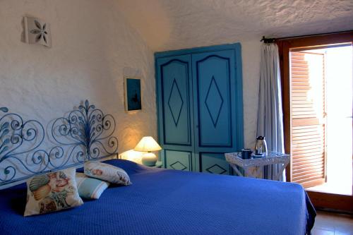 - une chambre avec un lit bleu et une fenêtre dans l'établissement I Mirti B&B, à San Pantaleo