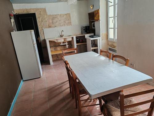 eine Küche mit einem Tisch und Stühlen sowie einem Kühlschrank in der Unterkunft ex domaine Chandelier in Anglade
