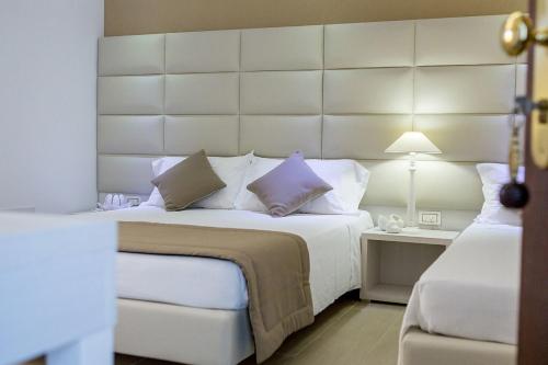 a bedroom with a large white bed with a large headboard at Hotel Vittoria in Vasto