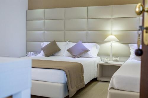 una camera da letto con un grande letto bianco con una grande testiera del letto di Hotel Vittoria a Vasto