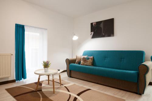 a living room with a blue couch and a table at Giovi Central Apartment in Cluj-Napoca