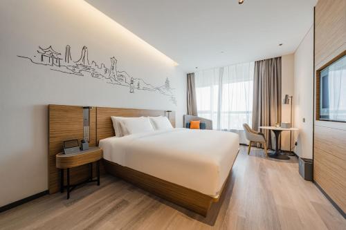 een hotelkamer met een groot bed en een bureau bij UrCove by HYATT Hangzhou Riverside CBD in Hangzhou