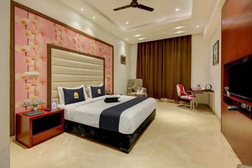 1 dormitorio con 1 cama grande y TV en Super Townhouse OAK Hotel C Pearls, en Nueva Delhi