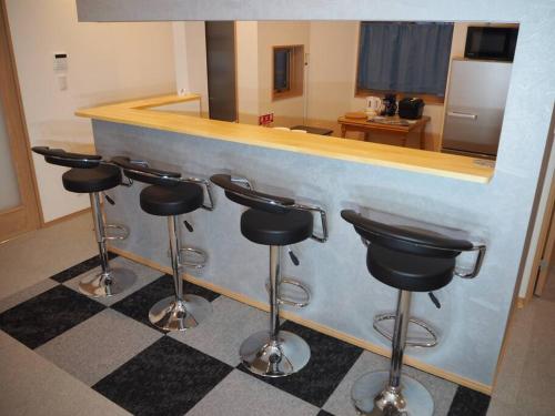 a bar with four stools in front of a counter at Holiday Villa ボストン in Niigata