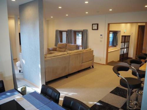 Holiday Villa ボストン في نيغاتا: غرفة معيشة مع أريكة وطاولة وكراسي