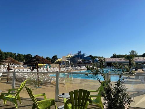 een zwembad met groene ligstoelen en een zwembad bij Mobilhome Ck135 Siblu Les Charmettes in Les Mathes