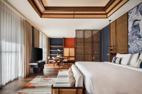 a hotel room with a large bed and a desk at The Meru Sanur in Sanur