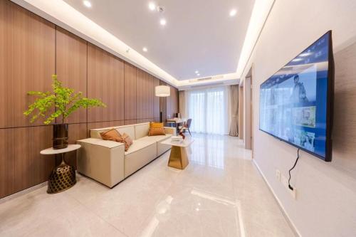 a living room with a white couch and a tv at Excellence International Apartment - Convention & Exhibition Center in Shenzhen