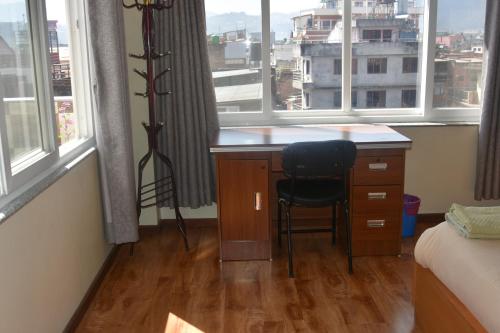 a bedroom with a desk with a chair and two windows at Shine Homestay Famille Francophone - Shine Home and Apartment in Kathmandu