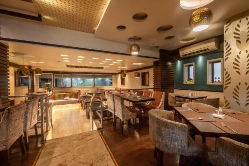 a restaurant with tables and chairs in a room at Hotel Le Grande - Mumbai International Airport in Mumbai