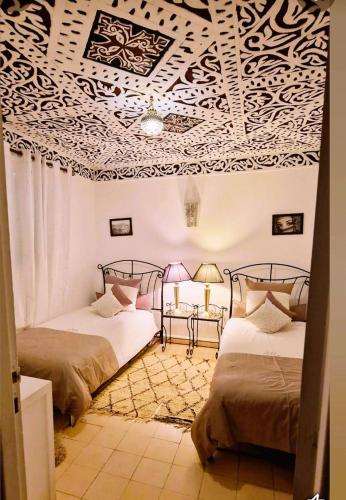 two beds in a room with a white ceiling at Riad Dar Sofian in Zagora